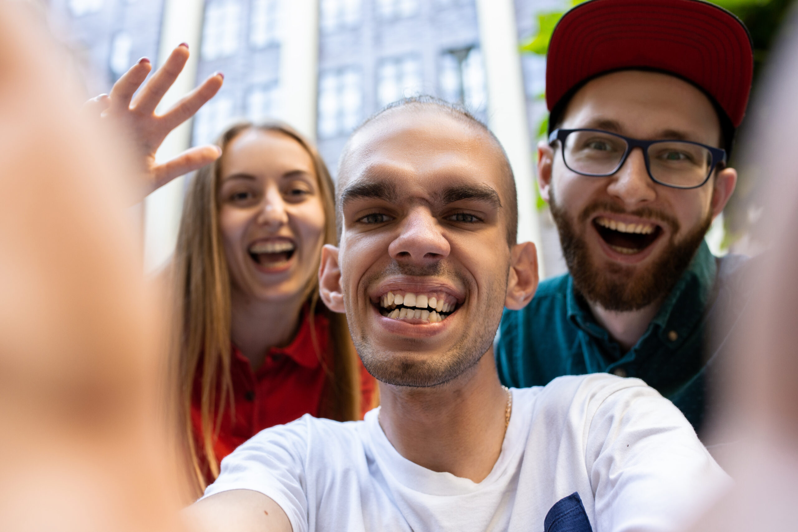 A woman and two men smiling while taking a selfie.