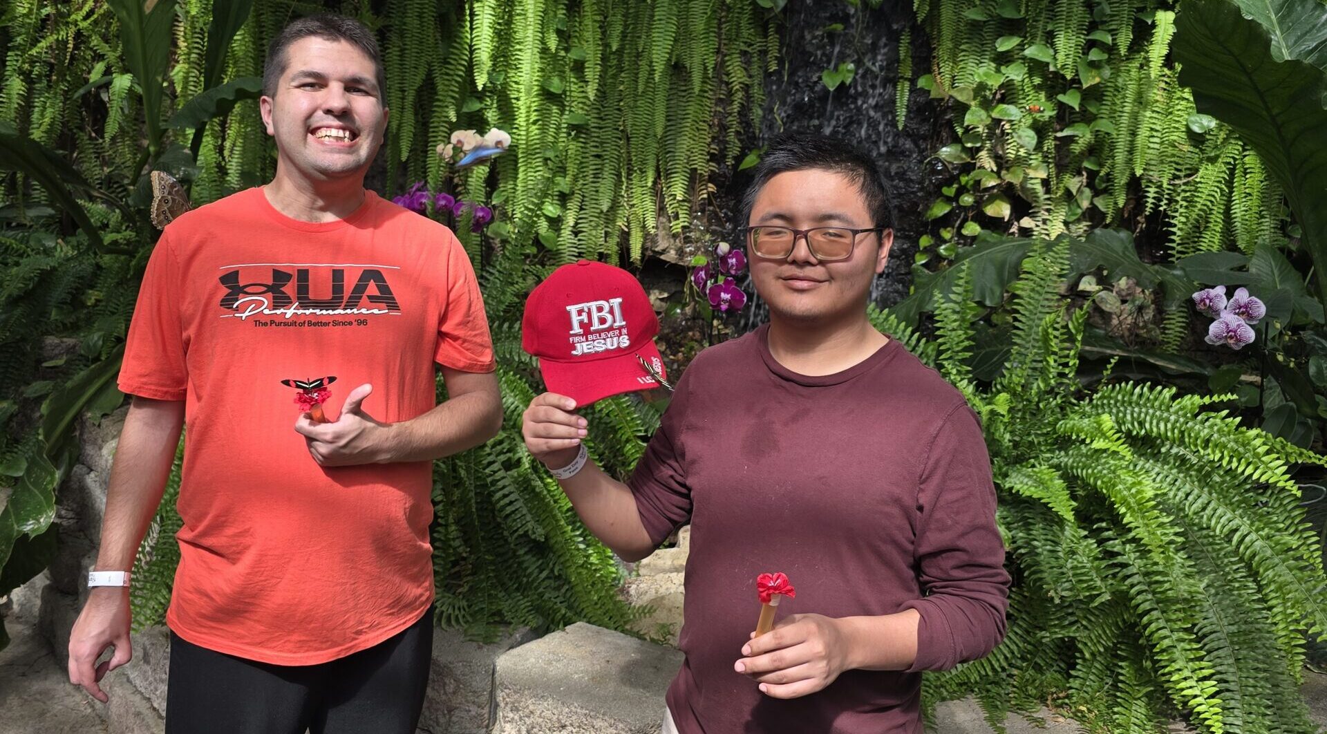 Two men standing in a greenhouse, smiling.